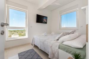 a white bedroom with a bed and two windows at Villa Buzuk in Vodice +37 photos