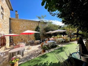 a patio with tables and chairs and umbrellas at Le Manoir du Raveyron in Vallon-Pont-dʼArc