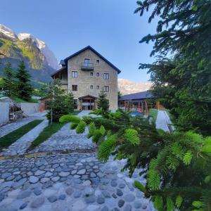 una casa en las montañas con un camino de piedra en Hotel Margjeka, en Valbonë
