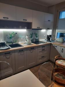 una cucina con armadi bianchi, lavandino e ripiani di Apartament Jak w Domu a Zamość