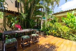 un patio con tavoli e sedie su una terrazza in legno di Suites de Charme Amoremio a Arraial d'Ajuda