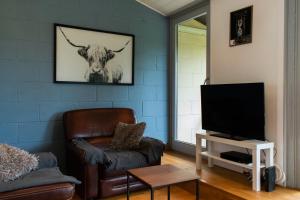 a living room with a leather chair and a television at Le Chalet de Gaume in Virton