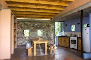 cocina con mesa de madera y pared de piedra en Las Rukas en San Javier
