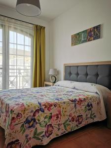 a bedroom with a bed with a floral bedspread and a window at Cosy duplex in Agaete with WIFI in Agaete