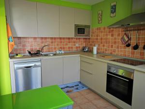 a kitchen with white cabinets and green walls at Cosy duplex in Agaete with WIFI in Agaete