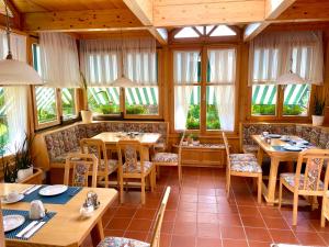 a restaurant with wooden tables and chairs and windows at Pension Thermenland in Loipersdorf bei Fürstenfeld