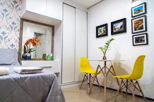 a bedroom with a table and two yellow chairs at Flat da Vila in Viçosa do Ceará