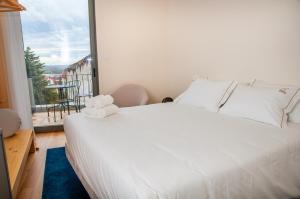 ein Schlafzimmer mit einem weißen Bett und einem Balkon in der Unterkunft Cravo’s Heritage House in Pinhel + 27 Fotos