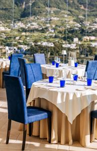 un restaurant avec des tables avec des chaises bleues et une vue dans l'établissement San Montano Resort & Spa, à Ischia