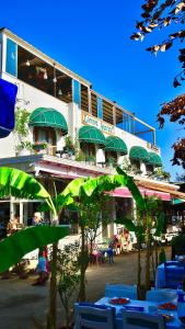a building with green umbrellas and tables and chairs at Liman Hotel Gümüslük - Adult Only in Bodrum City