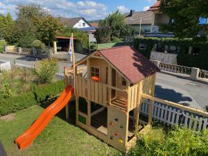 a wooden play house with an orange slide at Frankenwaldwohnung in Stockheim