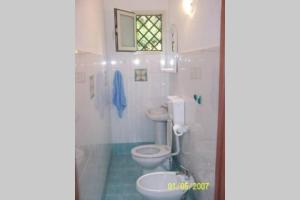 Un baño blanco con inodoro y ventana. en CASA DELLE PALME GIARRE SICILIA A 3 KM DAL MARE, en Giarre