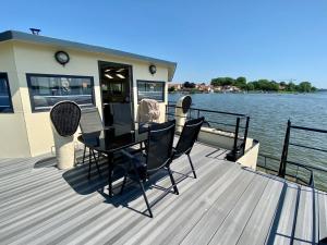 a deck with a table and chairs on a boat at Island-dreams Hausboote Groth & Rhin in Schleswig
