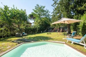 a swimming pool with a chair and an umbrella at Villa Lia - Apartment in Villa with private garden and Pool in Florence