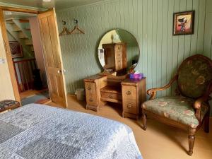 a bedroom with a mirror and a bed and a chair at À la croisée des sommets in Notre-Dame-Des-Bois