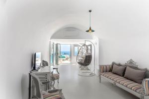 a living room with a couch and a table and chairs at Pearl on the Cliff Hotel & Suites by Pearl Hotel Collection in Imerovigli