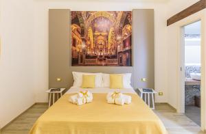 a bedroom with a large yellow bed with a painting on the wall at Barlaman Luxury Rooms in Palermo
