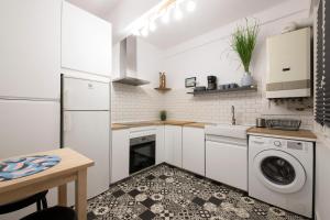 a kitchen with white cabinets and a washer and dryer at Playa Zurriola in San Sebastián