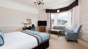 1 dormitorio con cama, sofá y TV en Fisher's Hotel, en Pitlochry