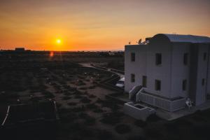 a sunset behind a building in a field at Abelonas Houses in Foinikiá