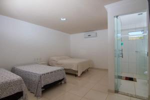 a bedroom with two beds and a glass shower at Pouso da Soraya in Rio de Contas