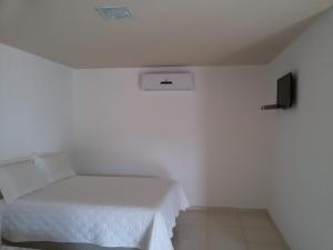 a white room with a bed and a tv at Pouso da Soraya in Rio de Contas +3 photos
