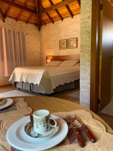 a room with a bed and a table with a plate of food at Chale Villa do Valle in Monte Verde