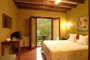 a bedroom with a bed and a desk and a window at La Ablaneda in Soto de Cangas
