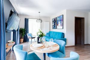 een woonkamer met een tafel en blauwe stoelen bij Apartamenty Kozubnik - Apartament 16 z dużym tarasem in Porąbka