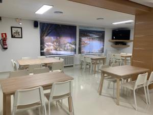 comedor con mesas de madera y sillas blancas en Hostal La Paz, en Ossa de Montiel