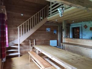 ein Holzzimmer mit einem Holztisch und einer Treppe in der Unterkunft Refuge Sous La Joux in Les Moussières