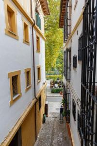 an alley between two buildings with a person walking down it at Meraki Suites Albaycin in Granada