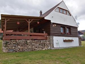 ein Holzhaus mit einer Steinmauer in der Unterkunft Šumavská rekreační chalupa in Pohorsko