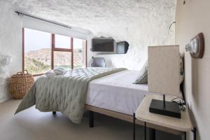 Habitación blanca con cama y ventana en Casa túnel Nido de Águilas en Alcalá del Júcar