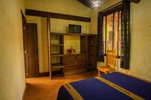 a bedroom with a bed and a cabinet and a window at Hotel Maya Ik' in Antigua Guatemala