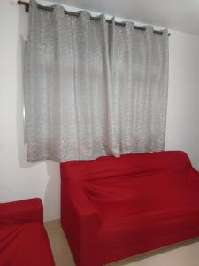 un sofá rojo sentado frente a una ventana en Apartamento Boqueirao en Praia Grande
