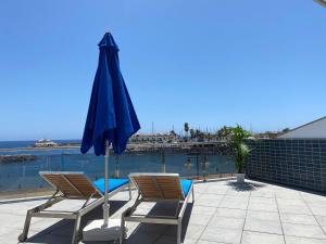 zwei Stühle und ein Sonnenschirm neben einem Swimmingpool in der Unterkunft Billy's Beachfront Apartment with pool access in Puerto de Mogán