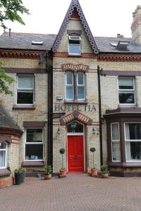 a brick building with a red door on a brick driveway at Hotel Tia in Liverpool