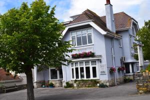 a white house with a tree in front of it at Swanage Haven Boutique Guest House in Swanage