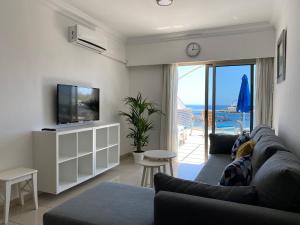 a living room with a couch and a tv at Billy's Beachfront Apartment with pool access in Puerto de Mogán