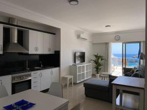 a kitchen and living room with a view of the ocean at Billy's Beachfront Apartment with pool access in Puerto de Mogán