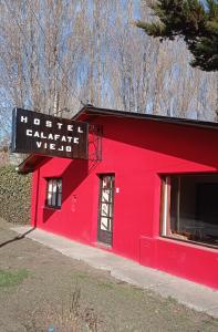 a red building with a sign on the side of it at Calafate Viejo Hostel in El Calafate