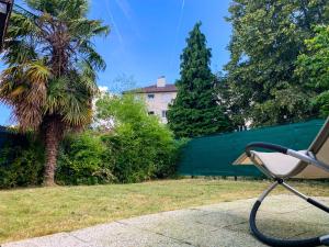 a park bench sitting on a sidewalk next to a palm tree at Joli studio avec jardin - Gare RER C -proche PARIS in Brétigny-sur-Orge