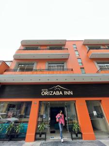 una mujer parada en la puerta de un edificio naranja en Orizaba Inn en Orizaba