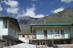 un edificio con balcone con vista sulle montagne sullo sfondo di Kera Guest House a Kazbegi