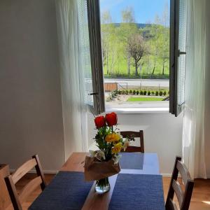 une table avec un vase de fleurs et une fenêtre dans l'établissement Apartmány HABR, à Nové Město pod Smrkem