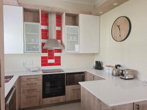 a kitchen with white cabinets and a clock on the wall at Modern Executive Unit in East London