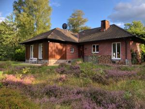 una casa de ladrillo rojo con un campo de flores púrpuras en Landhaus mitten in der Lüneburger Heide, en Undeloh