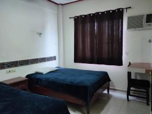 een slaapkamer met 2 bedden, een bureau en een raam bij HOTEL CASA VEINTITRES in Ciudad del Carmen