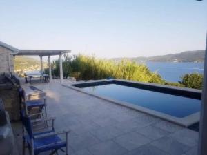 una piscina con sedie e vista sull'acqua di Green Marble Pool Cottage 3 BR in 2 adjoining stone buildings on a 2 acre private land a Viganj